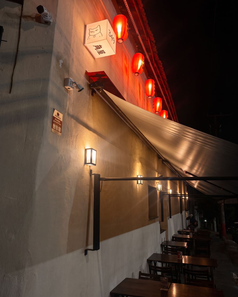 Lateral do Kadoya à noite, com toldo, luminárias e mesas na calçada